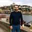 Homem maduro de aparência portuguesa com fundo urbano da cidade do Porto, cliente da reparação de termoacumulador.